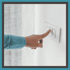 A hand pressing a light switch in a room