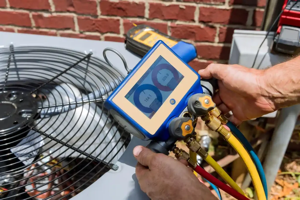 A person holding gauges over a AC unit outside a house or building.